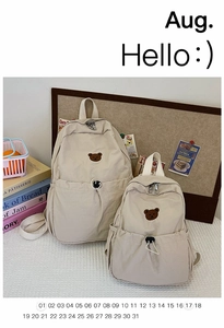 Détails de deux sacs à dos en toile crème avec broderie d'ours de tailles différentes