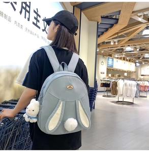 Detail of light blue nylon rabbit backpack featuring 3D ears and plush bunny charm