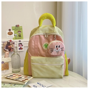 Detail of color-block kids backpack featuring a cute cartoon piglet pendant on pink zipper