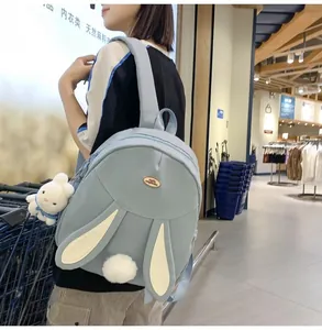 Detail of light blue rabbit backpack with long ears, pom-pom tail and plush bunny charm