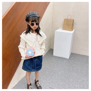 Fashionable toddler outfit with white knit sweater, denim skirt and flower-shaped crossbody bag