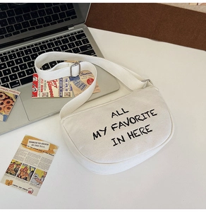 Detail of white canvas half-moon crossbody bag with black letter print and adjustable strap