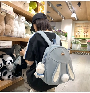 Close-up of light blue nylon backpack featuring cute rabbit ears and a plush tail detail