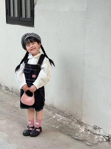 Full view of a pink mini crossbody bag with metal chain on a toddler model outfit