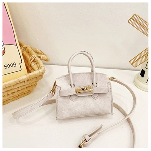 Détail d'un mini sac bandoulière beige clair avec tissu texturé et boucle dorée