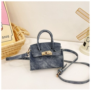 Détail d'un mini sac bandoulière en denim avec fermoir rotatif et double poignées sur table