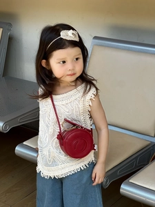 Close-up of a red round crossbody bag for kids with metal chain and faux leather strap
