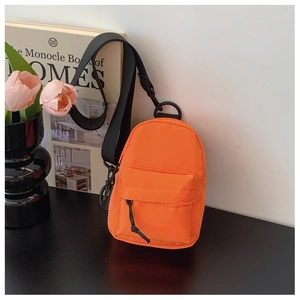Makroaufnahme einer orangen Mini-Umhängetasche aus Nylon mit schwarzem Riemen auf schwarzem Tisch