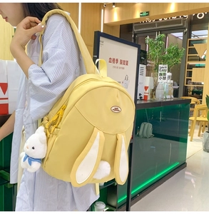 Detail view of yellow cute rabbit backpack with 3D ears and plush bunny charm accessory