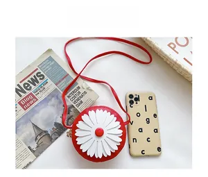 Size comparison of red daisy round crossbody bag next to a smartphone and a basket