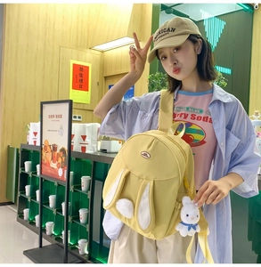 Detail of cute rabbit backpack in yellow with long ears and plush bunny charm
