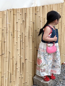 Detail of pink mini chain handbag styled with a denim vest and vintage print dress