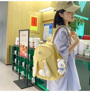 Detail view of yellow bunny backpack with cute 3D ears and plush pendant on model