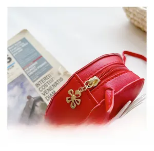 Close-up of a red kids round crossbody bag showing flower zipper and lychee leather