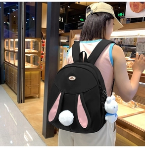 Detail of cute black bunny backpack with long pink ears and a plush rabbit charm
