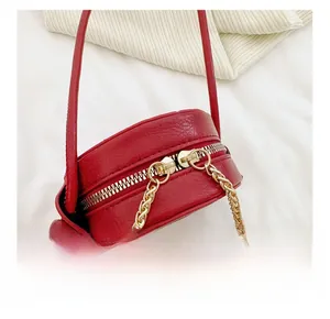 Detail view of smooth metal double zippers on a red leather kids circular crossbody bag