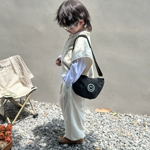 Kids black canvas crossbody bag with white smiley face and adjustable shoulder strap
