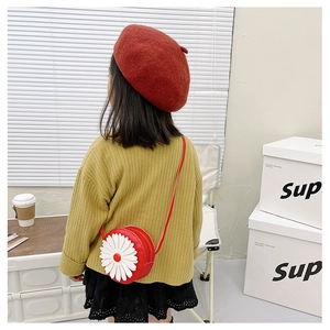 Rear view of a child wearing a red daisy crossbody bag with a red beret and yellow top