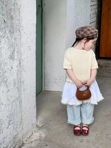 Detail shot of a brown crescent handbag with chain strap and stylish kid outfit