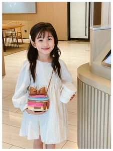 Detail of a child wearing the colorful woven crossbody bag with a brown leather bow