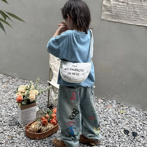 Kids fashion set with light blue t-shirt, graffiti wide-leg jeans, and white canvas crossbody bag