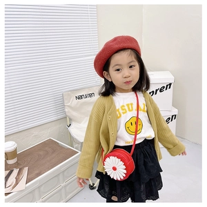 Detail of red daisy round crossbody bag styled with a yellow knit cardigan and red beret
