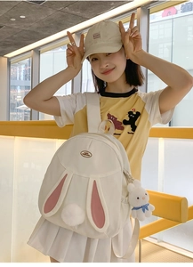 Detail of cute rabbit ears and plush bunny charm on white nylon backpack for women
