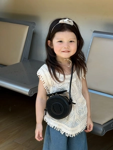 Toddler minimalist black round crossbody bag with chain strap shown on a young model