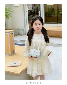 Detail of blue embroidered child bag with white pearls and gold chain on yellow dress
