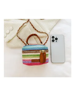 Mini woven crossbody bag with rainbow stripes next to a smartphone for size detail