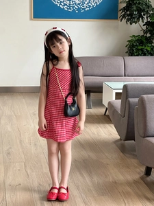 Detail of a red gingham toddler dress with bow straps and matching black mini bag