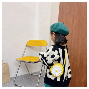 Kid modeling a daisy round crossbody bag with a knit sweater and green beret