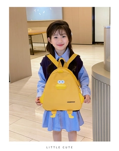 Vue de face d'un sac à dos canard jaune en 3D porté par un enfant en intérieur
