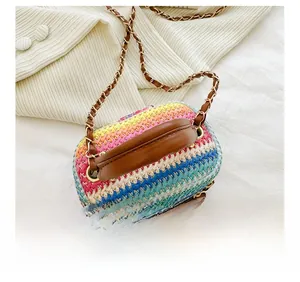 Detail of colorful woven mini bag featuring rainbow stripes and brown leather handle