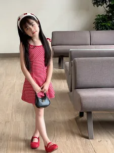 Close-up of a red and white checkered girls' dress with delicate shoulder bow details