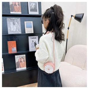 Girl's pink daisy round crossbody bag shown on model with white knit sweater