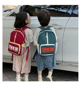 Detail of red and green children's backpacks with THKIN lettering and side mesh pockets
