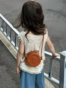 Close-up of brown round leather crossbody bag for children on a stylish outfit