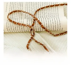 Detail of woven chain shoulder strap made with brown leather and gold metal hardware