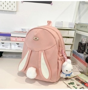 Detail of pink cartoon rabbit backpack featuring long ears and white plush pom-pom tail