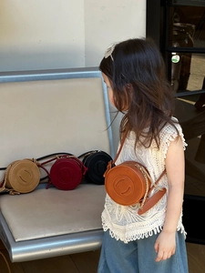 Detail showing round kids shoulder bag in multiple colors with metallic chain strap