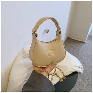Close-up of beige leather mini half-moon bag featuring AIR AIR embossed logo and gold chain