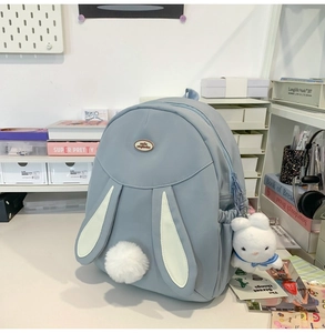 Detail view of a light blue bunny backpack with cute 3D ears and a plush rabbit charm