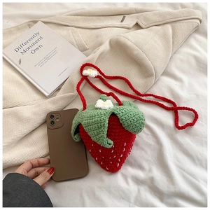 Detail of handmade crochet strawberry bag showing red yarn texture and leaf design