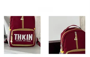 Detail view of red canvas backpack with yellow zippers and white lettering prints