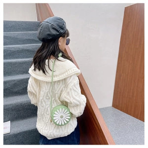 Detail of a green round crossbody bag for kids with 3D white daisy flower and knit sweater