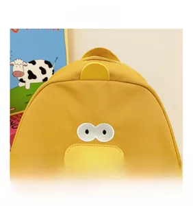 Détail du tissu en toile et de la face de canard brodée sur le sac à dos jaune pour enfants
