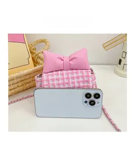 Pink checkered girl's crossbody bag with bow detail compared to a phone for size reference