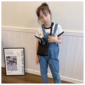 Close-up of a minimalist black mini crossbody bag worn by a young girl with casual outfit
