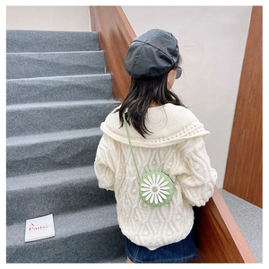 Close-up of mint green round crossbody bag with daisy decor on girl's shoulder